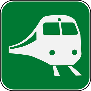 Image of green sign with train on railway tracks
